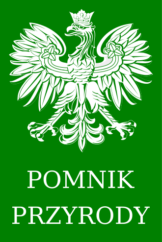 Biały orzeł w koronie na zielonym tle, pod nim biały napis "POMNIK PRZYRODY"