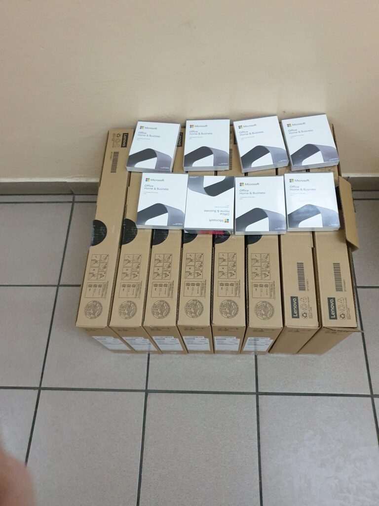 Sześć kartonów Lenovo ułożonych w rzędzie na podłodze, na nich osiem białych pudełek Microsoft Office Home & Business.