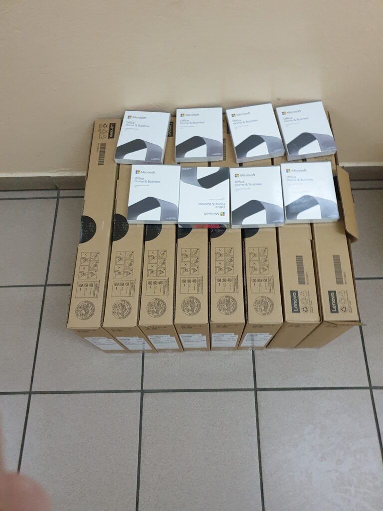 Osiem kartonowych pudełek Lenovo ustawionych obok siebie, na nich osiem białych opakowań Microsoft Office Home & Business.