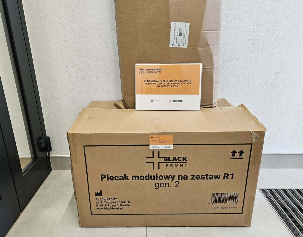 Dwa brązowe kartony, na większym napis "BLACK FRONT Plecak modułowy na zestaw R1 gen. 2", na mniejszym naklejka z informacją o dofinansowaniu programu ochrony ludności i obrony cywilnej.